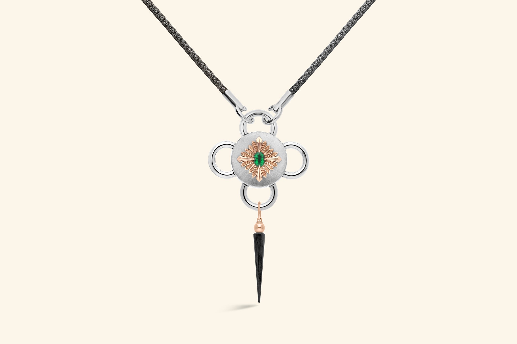 Collier Bolt, émeraude de ~0,80 carat sertie une fleur en or rose poli, elle-même posée sur un plateau en argent satiné. Une pampille en or rose et argent noirci. Chaine tricotée en argent noirci.