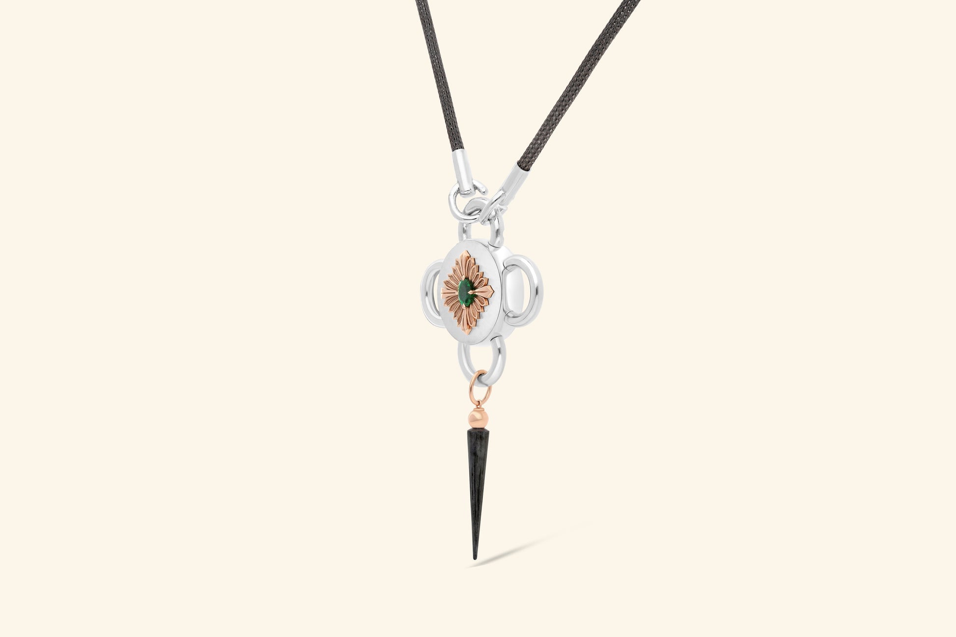 Collier Bolt, émeraude de ~0,80 carat sertie une fleur en or rose poli, elle-même posée sur un plateau en argent satiné. Une pampille en or rose et argent noirci. Chaine tricotée en argent noirci.